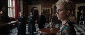 Movie still from “Enola Holmes” (2020), directed by Harry Bradbeer – A group of people standing around a room; Close Up shot, Over the shoulder angle