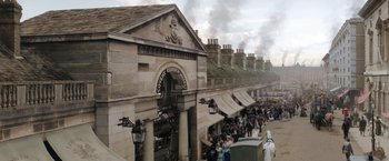Movie still from “Enola Holmes” (2020), directed by Harry Bradbeer – A group of people standing outside of a building; Extreme Wide shot, High angle