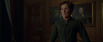 Movie still from “Enola Holmes” (2020), directed by Harry Bradbeer – An older woman in a green dress looking at the camera; Medium shot, Low angle