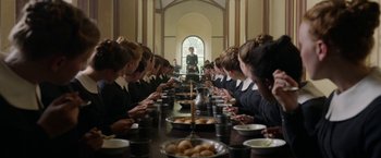 Movie still from “Enola Holmes” (2020), directed by Harry Bradbeer – A group of people sitting around a long table; Wide shot, High angle