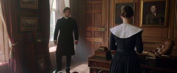 Movie still from “Enola Holmes” (2020), directed by Harry Bradbeer – A man and a woman standing in front of an antique chest in a room; Medium shot, Over the shoulder angle