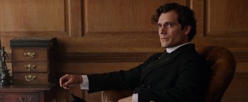 Movie still from “Enola Holmes” (2020), directed by Harry Bradbeer – A man sitting in a chair wearing a suit and tie; Close Up shot, Over the shoulder angle