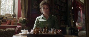 Movie still from “Enola Holmes” (2020), directed by Harry Bradbeer – A woman sitting at a table with a chess set; Close Up shot, High angle