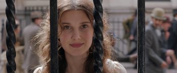 Movie still from “Enola Holmes” (2020), directed by Harry Bradbeer – A young woman with long brown curly hair and green eyes; Close Up shot, Over the shoulder angle