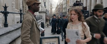 Movie still from “Enola Holmes” (2020), directed by Harry Bradbeer – A group of people walking down a street; Medium shot, Over the shoulder angle