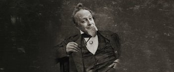 Movie still from “Enola Holmes” (2020), directed by Harry Bradbeer – An old man with a beard and a mustache is holding a pair of eyeglasses; Close Up shot, Low angle