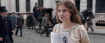 Movie still from “Enola Holmes” (2020), directed by Harry Bradbeer – A young woman is holding up a newspaper; Close Up shot, Over the shoulder angle