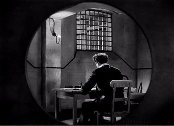 Movie still from “Kind Hearts and Coronets” (1949), directed by Robert Hamer – A man sitting at a table in front of a window; Wide shot, High angle