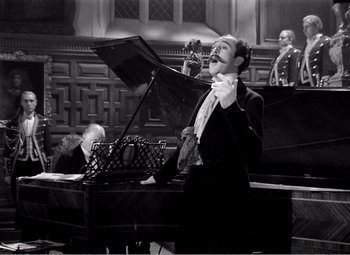 Movie still from “Kind Hearts and Coronets” (1949), directed by Robert Hamer – A black and white photo of a man playing a piano; Medium shot, High angle