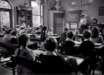 Movie still from “Kind Hearts and Coronets” (1949), directed by Robert Hamer – An old photo of a class room full of students; Wide shot, High angle