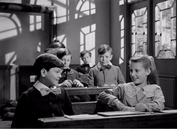Movie still from “Kind Hearts and Coronets” (1949), directed by Robert Hamer – A black and white photo of a group of children in a classroom; Medium shot, High angle
