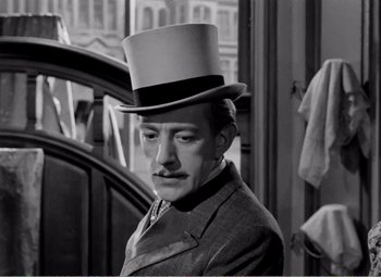 Movie still from “Kind Hearts and Coronets” (1949), directed by Robert Hamer – A black and white photo of a man wearing a top hat; Close Up shot, Over the shoulder angle