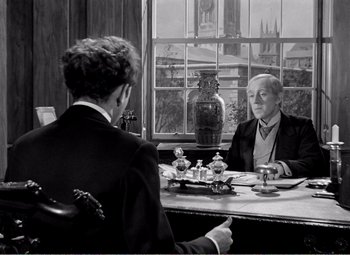 Movie still from “Kind Hearts and Coronets” (1949), directed by Robert Hamer – Two men sitting at a table in front of a window; Medium shot, Over the shoulder angle
