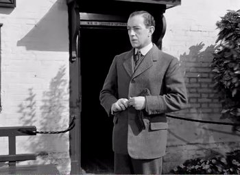 Movie still from “Kind Hearts and Coronets” (1949), directed by Robert Hamer – A man standing in front of a door way; Medium shot, Low angle