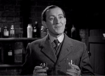 Movie still from “Kind Hearts and Coronets” (1949), directed by Robert Hamer – A black and white photo of a man holding a glass of wine; Close Up shot, Low angle