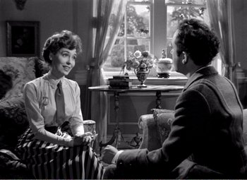 Movie still from “Kind Hearts and Coronets” (1949), directed by Robert Hamer – An old photo of a man and a woman sitting at a table; Medium shot, High angle