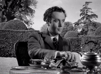 Movie still from “Kind Hearts and Coronets” (1949), directed by Robert Hamer – A black and white photo of a man sitting at a table; Medium shot, Low angle