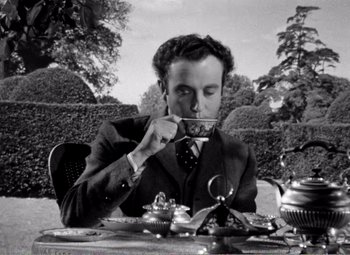 Movie still from “Kind Hearts and Coronets” (1949), directed by Robert Hamer – A black and white photo of a man taking a picture with a camera; Medium shot, High angle