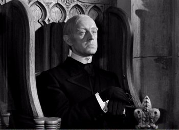 Movie still from “Kind Hearts and Coronets” (1949), directed by Robert Hamer – An old man sitting in a chair wearing a black suit; Medium shot, Low angle