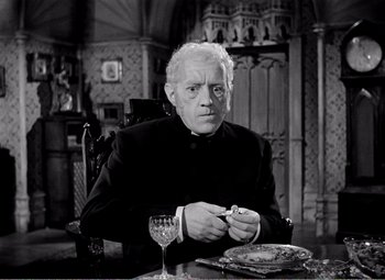 Movie still from “Kind Hearts and Coronets” (1949), directed by Robert Hamer – An older man sitting at a table with a glass of wine in front of him; Medium shot, High angle