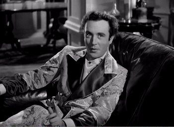 Movie still from “Kind Hearts and Coronets” (1949), directed by Robert Hamer – A black and white photo of a man sitting in a chair; Medium shot, High angle