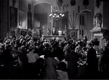Movie still from “Kind Hearts and Coronets” (1949), directed by Robert Hamer – A large group of people sitting in a room; Extreme Wide shot, High angle