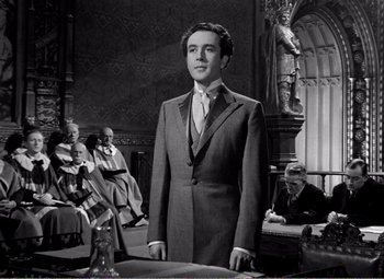 Movie still from “Kind Hearts and Coronets” (1949), directed by Robert Hamer – A black and white photo of a man in a suit and tie; Medium shot, Low angle