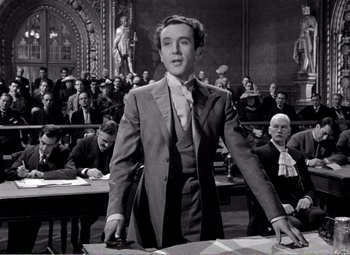 Movie still from “Kind Hearts and Coronets” (1949), directed by Robert Hamer – A man standing in front of a crowd in a courtroom; Medium shot, Low angle
