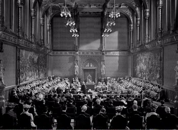 Movie still from “Kind Hearts and Coronets” (1949), directed by Robert Hamer – An old photo of a group of people sitting in a room; Extreme Wide shot, High angle