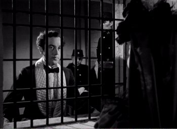 Movie still from “Kind Hearts and Coronets” (1949), directed by Robert Hamer – A black and white photo of a man in a jail cell; Medium shot, Low angle