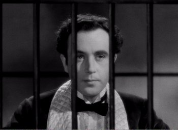 Movie still from “Kind Hearts and Coronets” (1949), directed by Robert Hamer – A black and white photo of a man behind bars; Close Up shot, Low angle