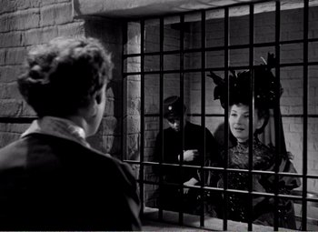 Movie still from “Kind Hearts and Coronets” (1949), directed by Robert Hamer – A man and a woman are in a jail cell; Medium shot, Over the shoulder angle