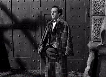 Movie still from “Kind Hearts and Coronets” (1949), directed by Robert Hamer – A black and white photo of a man in a suit and hat; Medium shot, Low angle