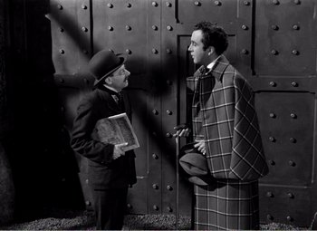 Movie still from “Kind Hearts and Coronets” (1949), directed by Robert Hamer – Two men are talking to each other in front of a door; Medium shot, High angle