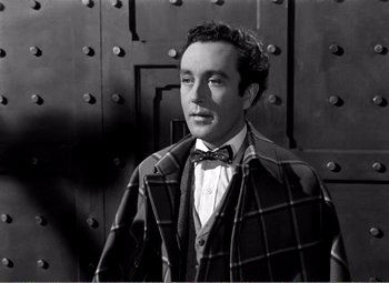 Movie still from “Kind Hearts and Coronets” (1949), directed by Robert Hamer – A black and white photo of a man wearing a suit and bow tie; Medium shot, Low angle