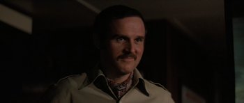 Movie still from “King Kong” (1976), directed by John Guillermin – A person wearing a shirt and tie; Close Up shot, Over the shoulder angle
