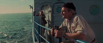 Movie still from “King Kong” (1976), directed by John Guillermin – A man on a boat with binoculars looking out over the water; Medium shot, Over the shoulder angle