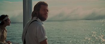 Movie still from “King Kong” (1976), directed by John Guillermin – A man with long hair and a beard standing in front of a body of water; Close Up shot, Low angle
