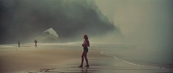 Movie still from “King Kong” (1976), directed by John Guillermin – A woman standing on a beach near the ocean; Extreme Wide shot, Low angle