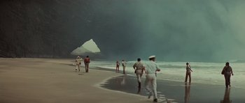 Movie still from “King Kong” (1976), directed by John Guillermin – A group of people walking along the beach; Extreme Wide shot, High angle