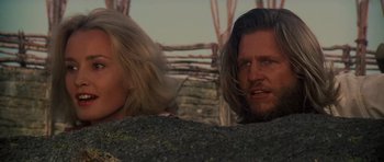 Movie still from “King Kong” (1976), directed by John Guillermin – A man and a woman standing next to each other in front of a stone wall; Close Up shot, Low angle