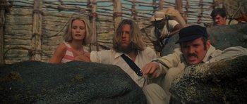 Movie still from “King Kong” (1976), directed by John Guillermin – A man with a long beard sitting next to a woman; Medium shot, Low angle