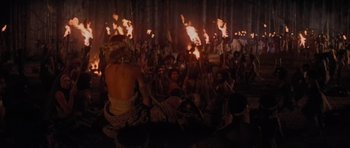 Movie still from “King Kong” (1976), directed by John Guillermin – A crowd of people sitting around a fire; Wide shot, High angle