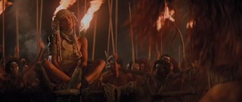 Movie still from “King Kong” (1976), directed by John Guillermin – A group of people are gathered around a fire; Medium shot, High angle