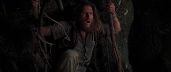 Movie still from “King Kong” (1976), directed by John Guillermin – A man with long hair and a long beard is holding a stick; Medium shot, Low angle
