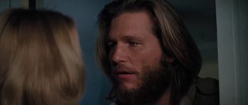 Movie still from “King Kong” (1976), directed by John Guillermin – A person with long hair and a beard; Close Up shot, Over the shoulder angle