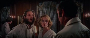 Movie still from “King Kong” (1976), directed by John Guillermin – A man and a woman standing next to each other in front of another man; Medium shot, Over the shoulder angle