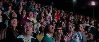 Movie still from “King Kong” (1976), directed by John Guillermin – A group of people in a room watching a show; Wide shot, High angle
