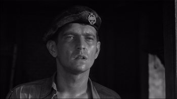 Movie still from “King Rat” (1965), directed by Bryan Forbes – A black and white photo of a man wearing a hat; Close Up shot, Low angle