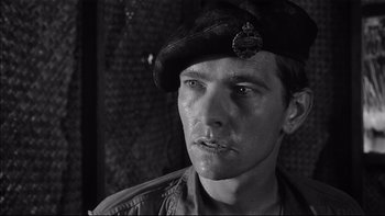 Movie still from “King Rat” (1965), directed by Bryan Forbes – Black and white photograph of a man wearing a hat; Close Up shot, Low angle